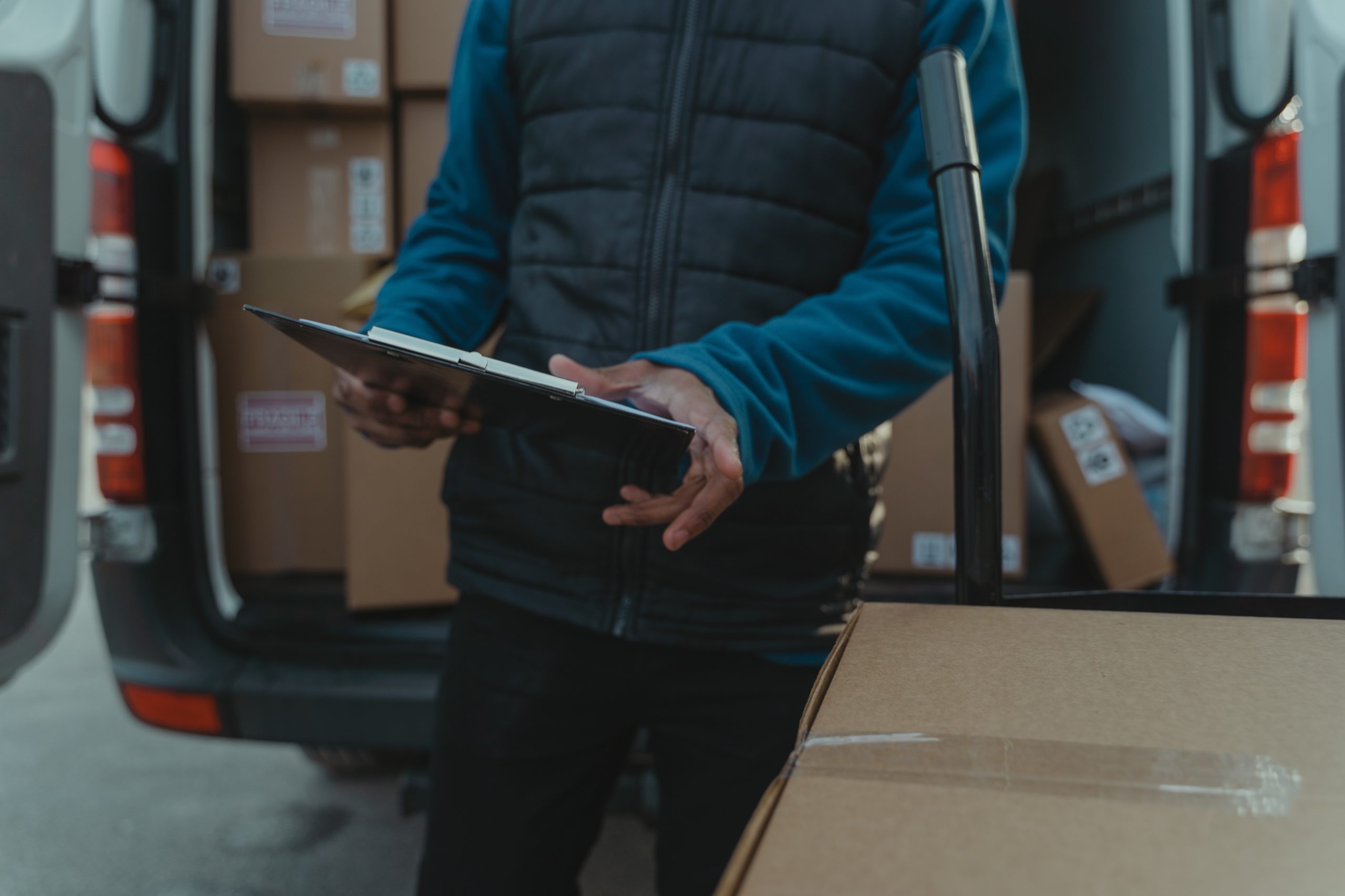 pexels-tima-miroshnichenko-6169181 delivery man checking his clipboard in front of his delivery van