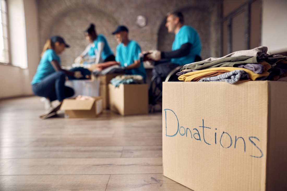 Donation box full of clothes with volunteers working in the background.