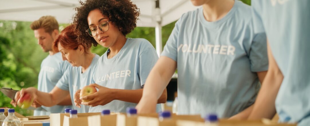 Portrait of a Black Latina Female Volunteer Preparing Free Food Delivery for Low Income People. Charity Workers and Members of the Community Work Together in Local Humanitarian Aid Donation Center.